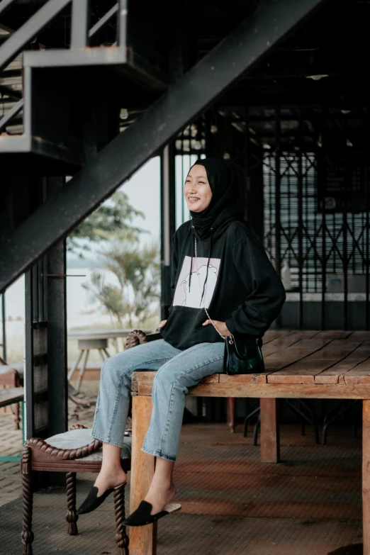 a young woman sitting on top of a wooden bench