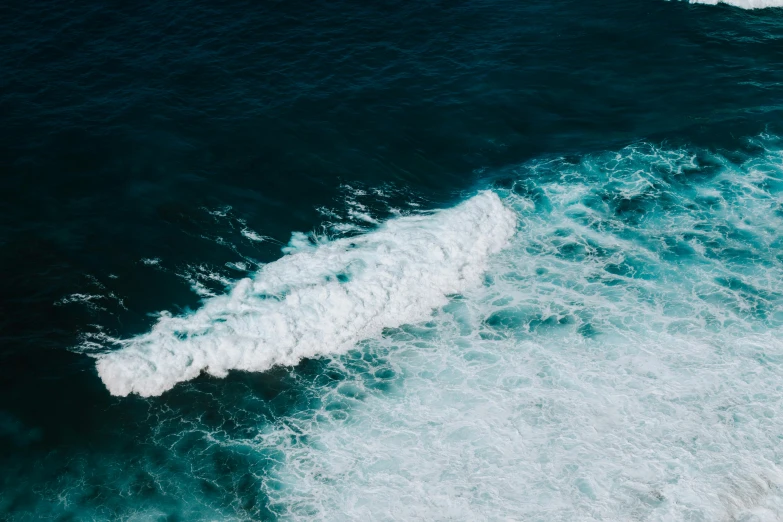 an aerial view of a wave crashing into the ocean