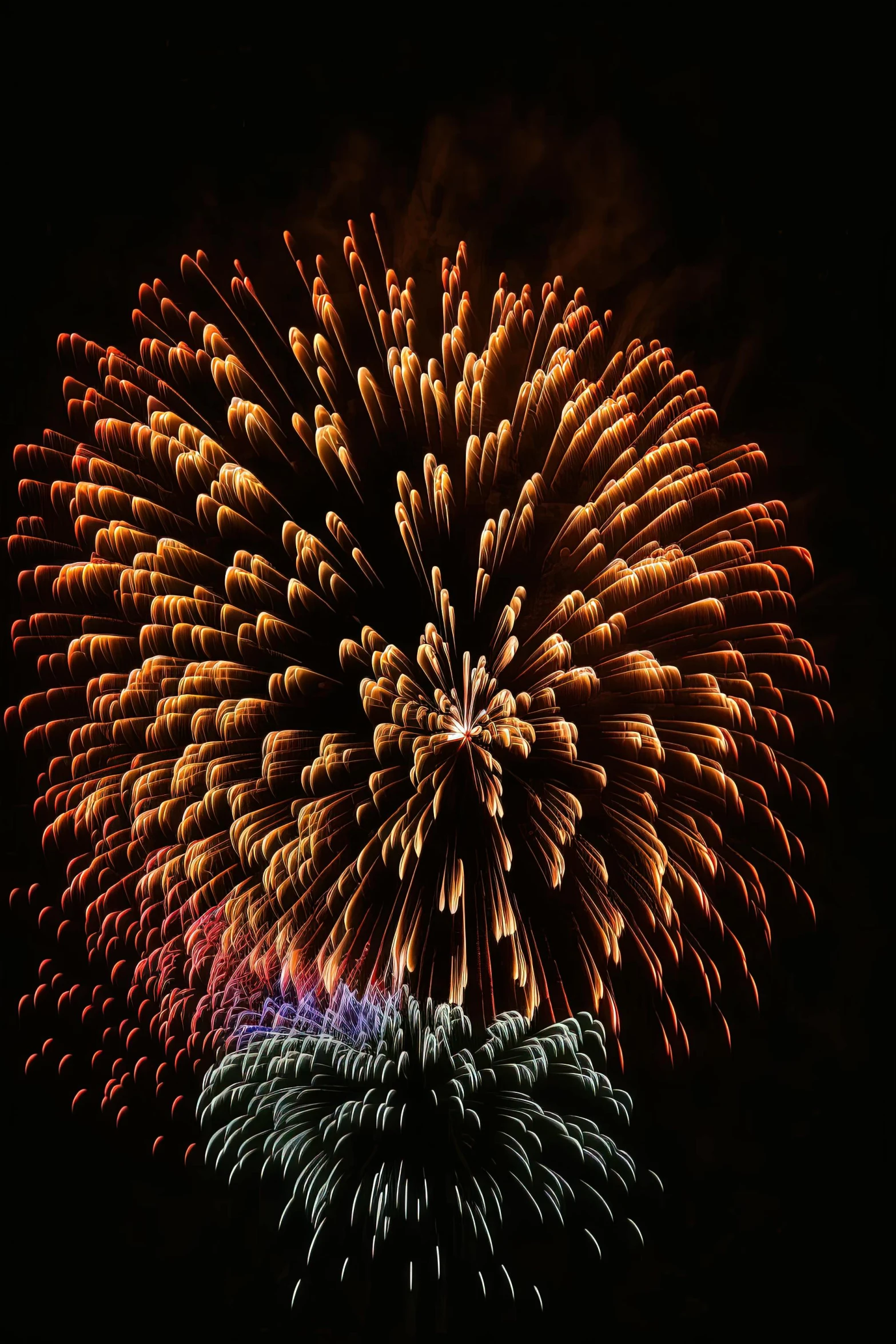 fireworks displayed over water and surrounded by dark sky