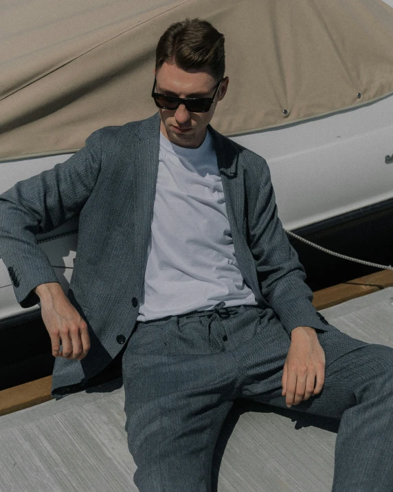 a man in sunglasses sits on a dock by his boat