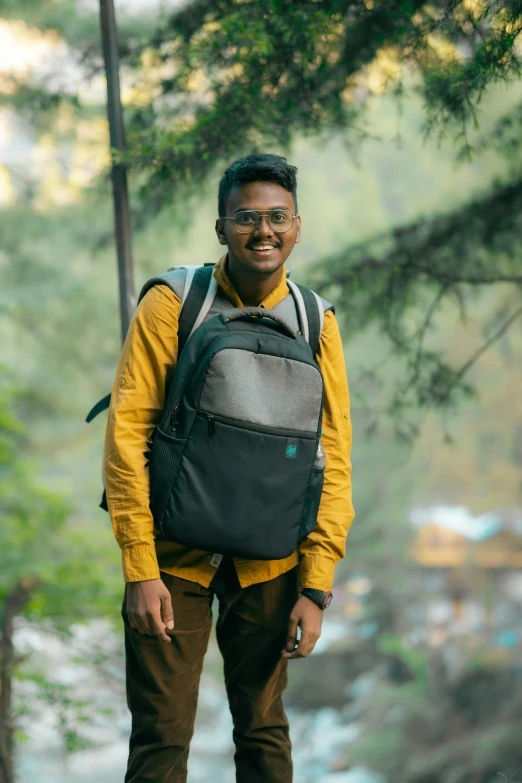 a man standing in the forest holding a backpack