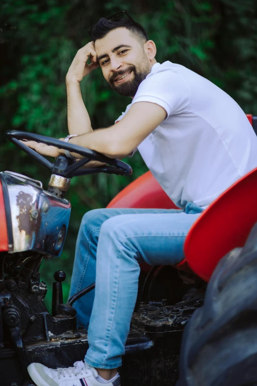 the man in white shirt is sitting on a red tractor