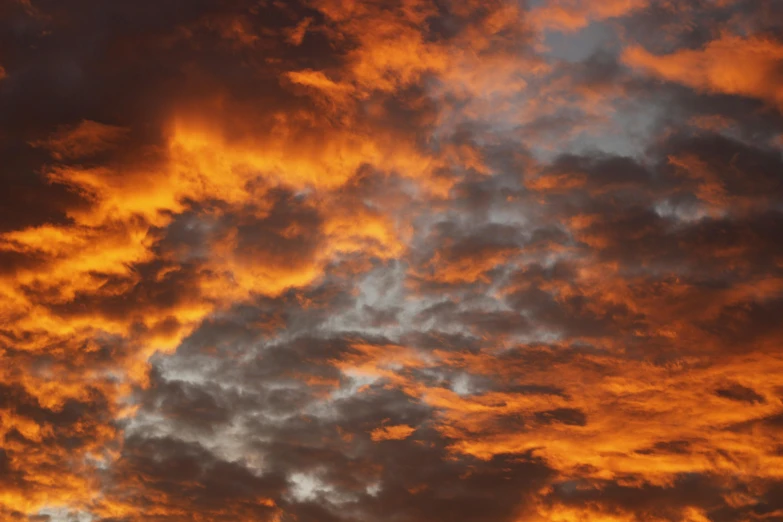 a jet airliner flying through a cloudy sky at sunset