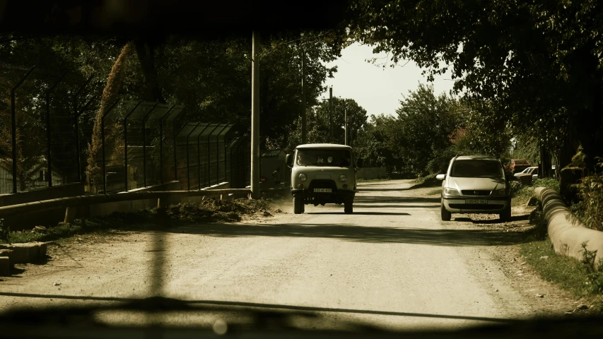 two trucks parked on a road with trees and fence in the background