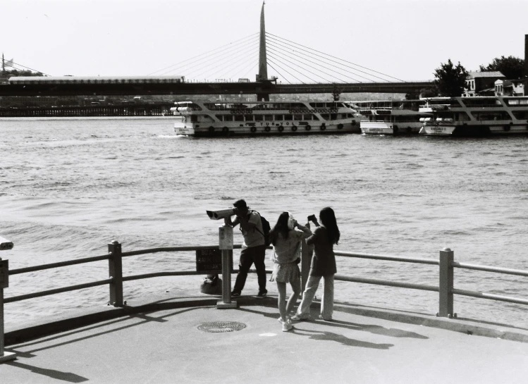 four young adults standing on a pier looking at water