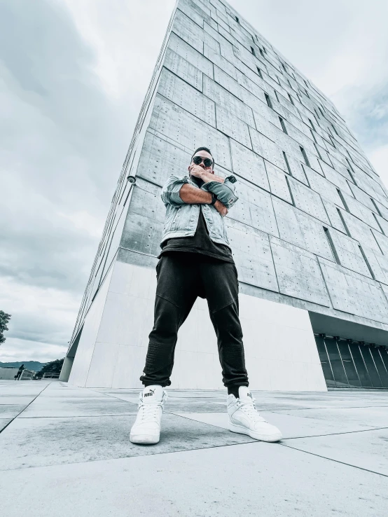 a man poses for a picture while leaning on a building