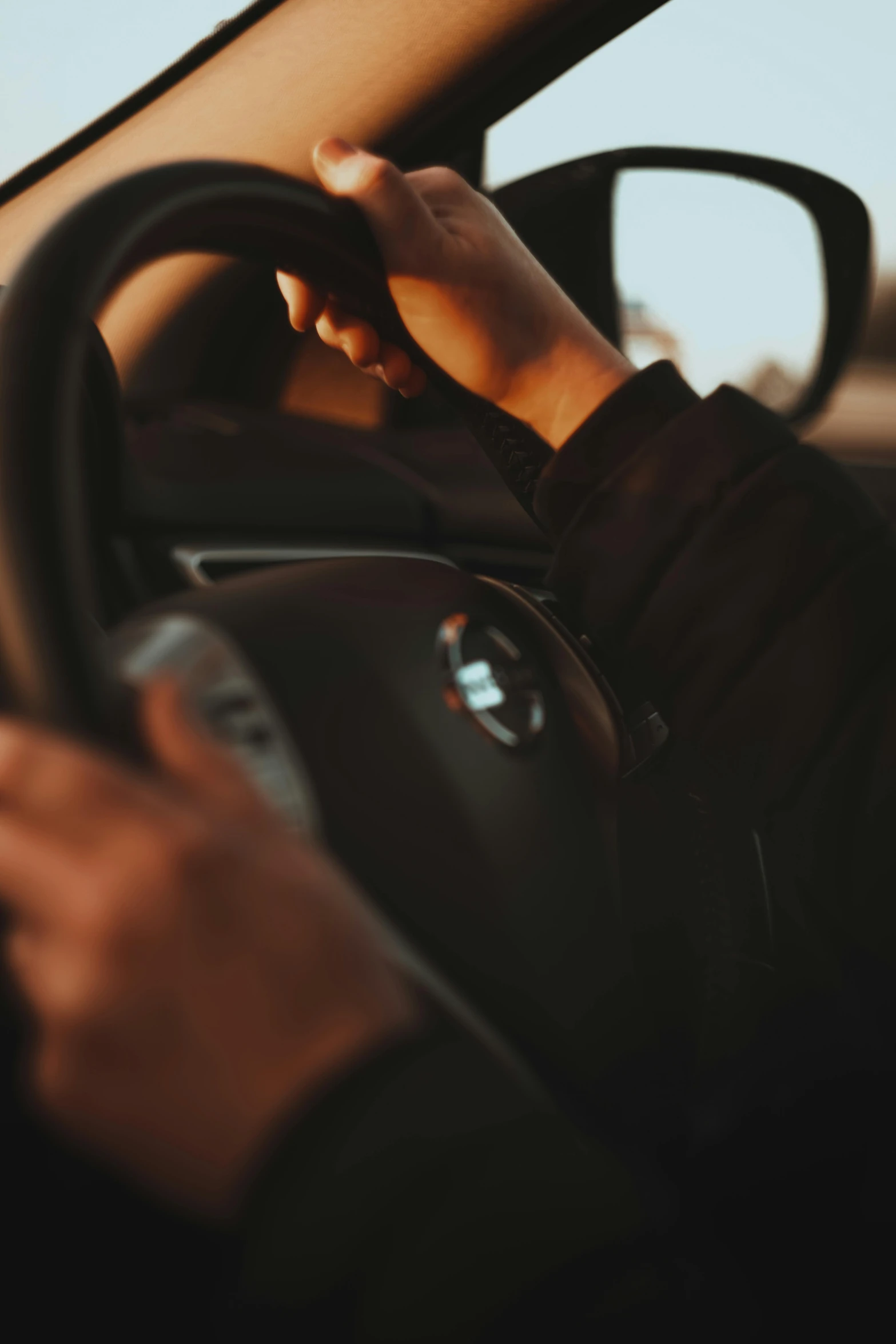 a person driving the car with his hand on the steering wheel