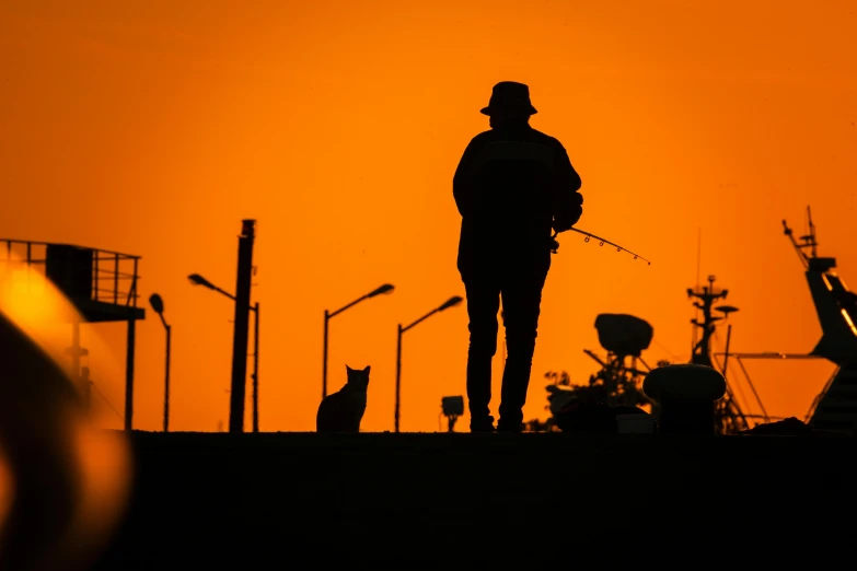 an orange sky silhouetted against a fishing silhouette