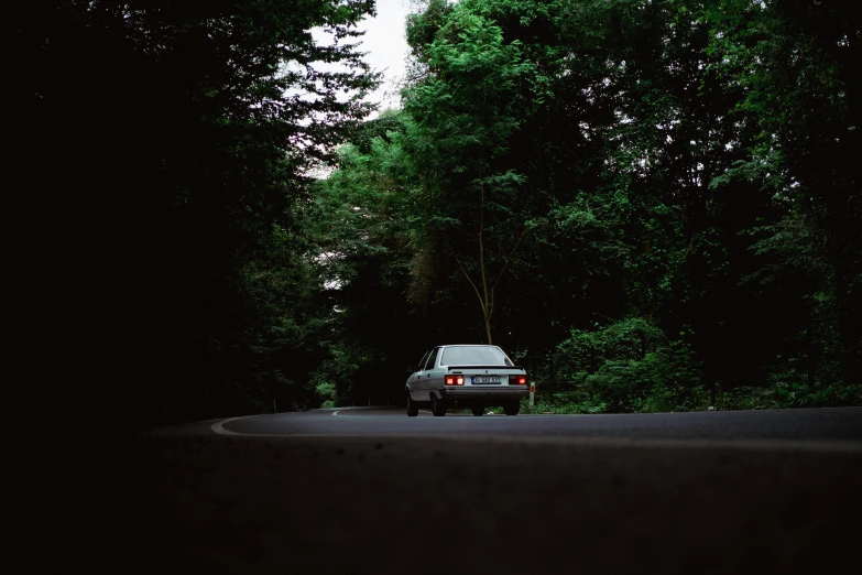 an automobile is parked on the side of the road near some trees