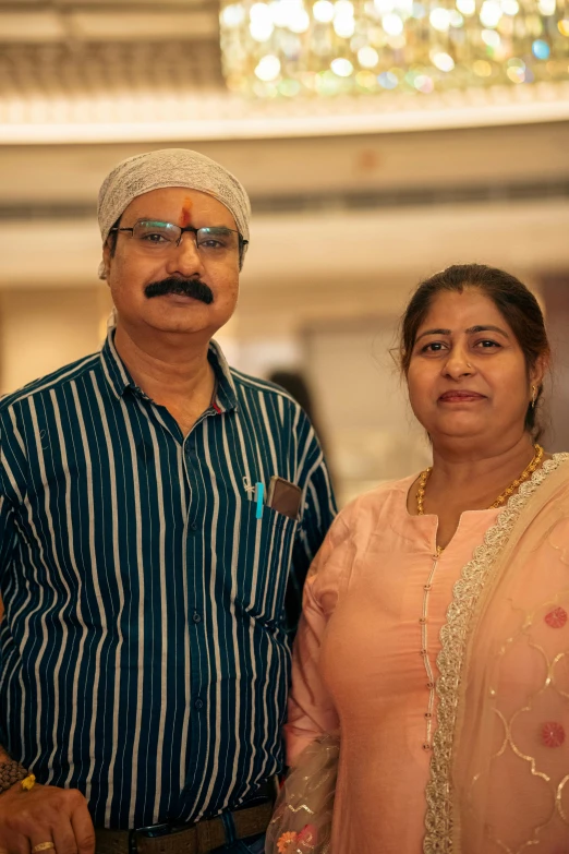 a man and a woman standing next to each other in front of a chandelier