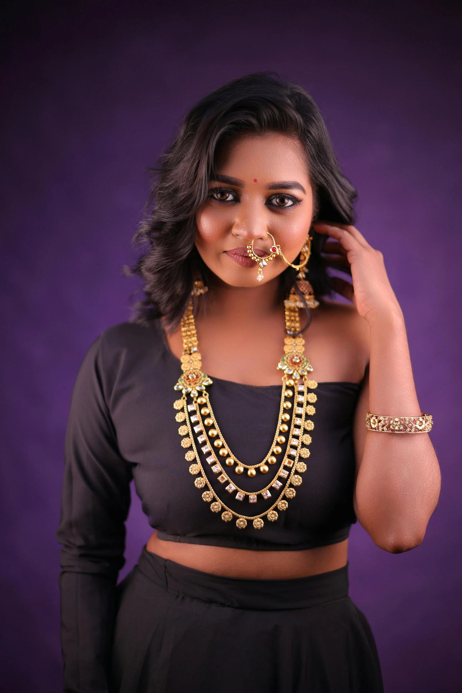 a  wearing jewellery and earrings in a black cropped top