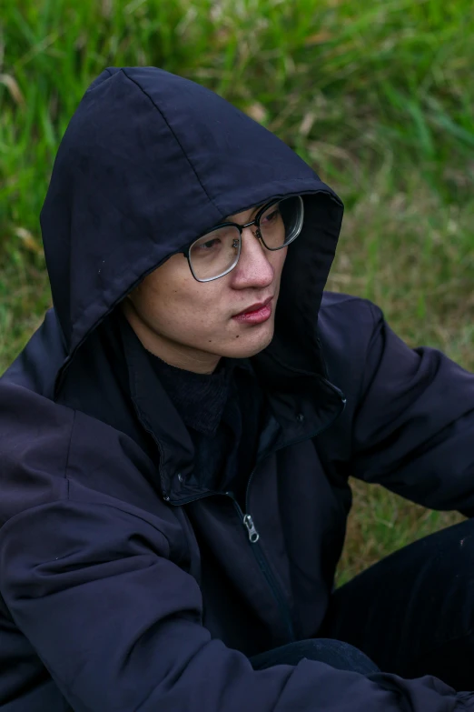 the man is wearing glasses and a hooded jacket