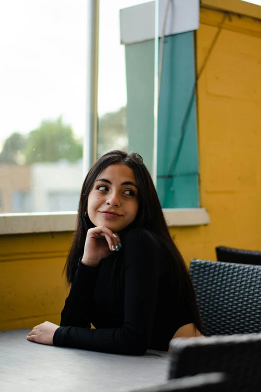 a woman sitting at a table posing for a po