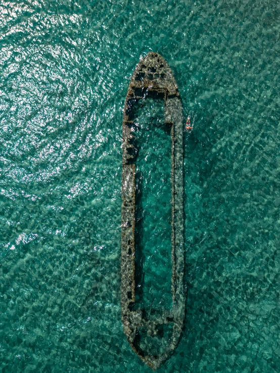 a boat floating in the ocean next to a rock