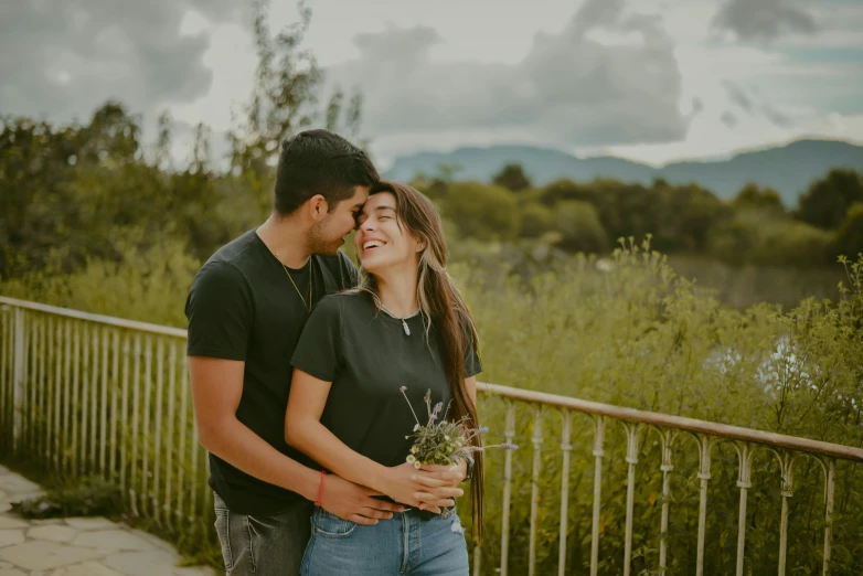 a young couple standing in front of mountains and trees