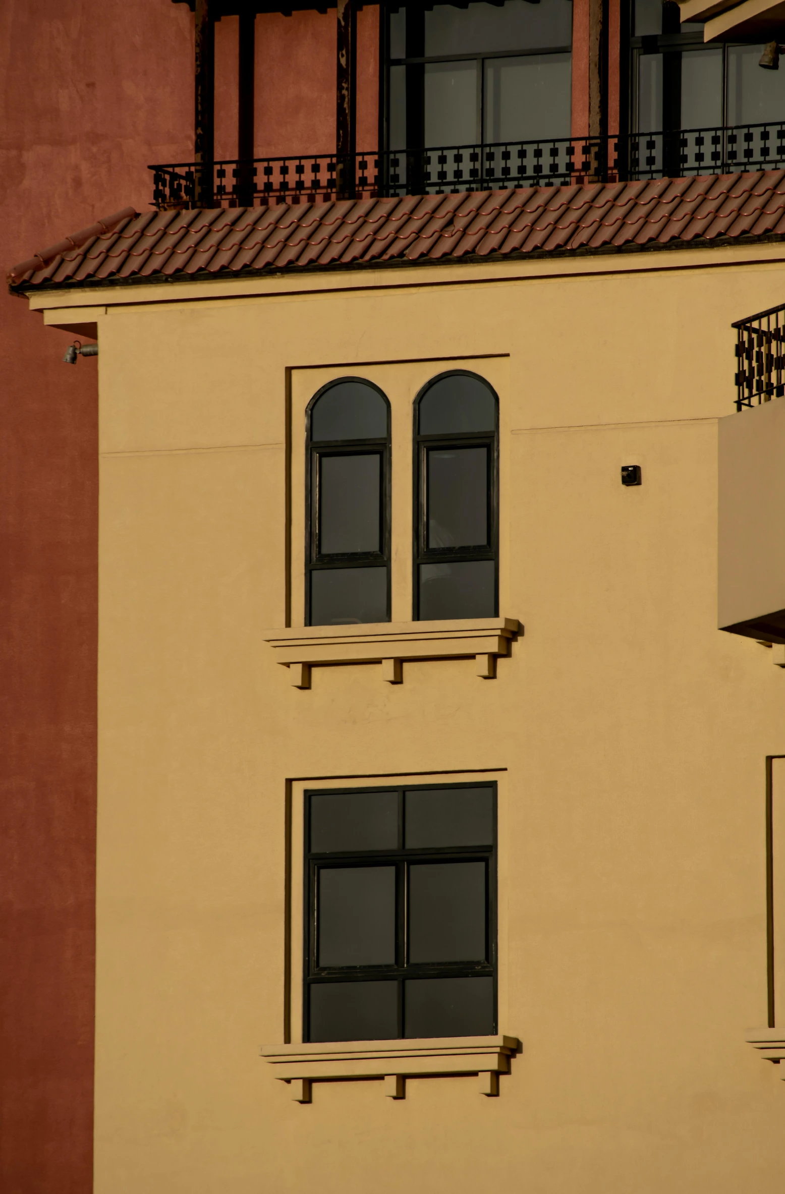 a red building with some black windows and a cat standing outside