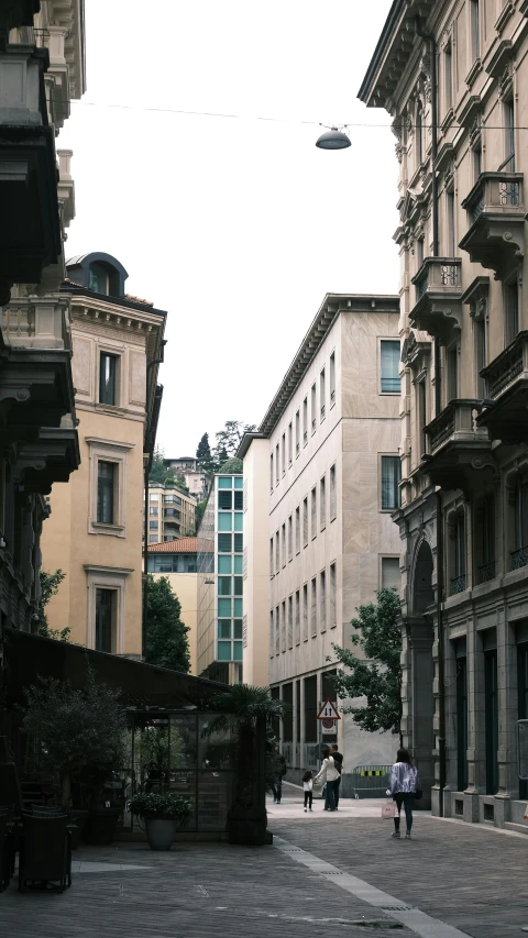 several people walking along an urban road in between buildings