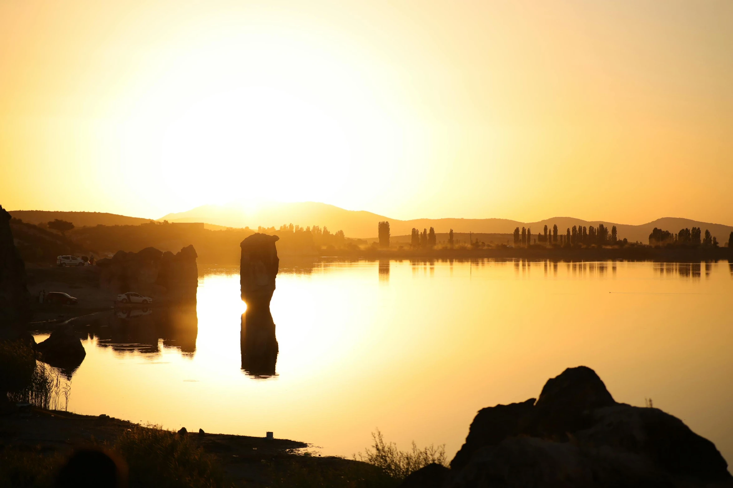 people on their bikes are walking by a lake at sunset