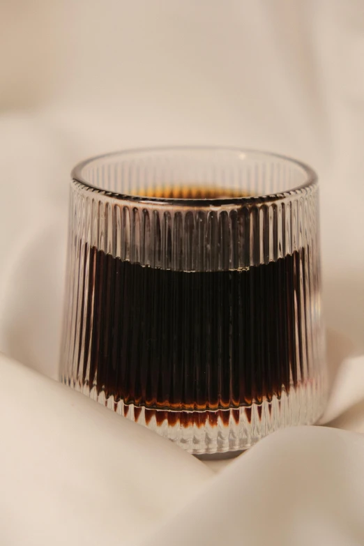 a glass filled with black liquid on top of a white cloth