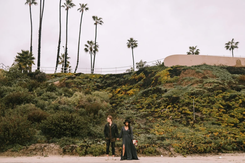 an old couple stands on a hill side holding hands