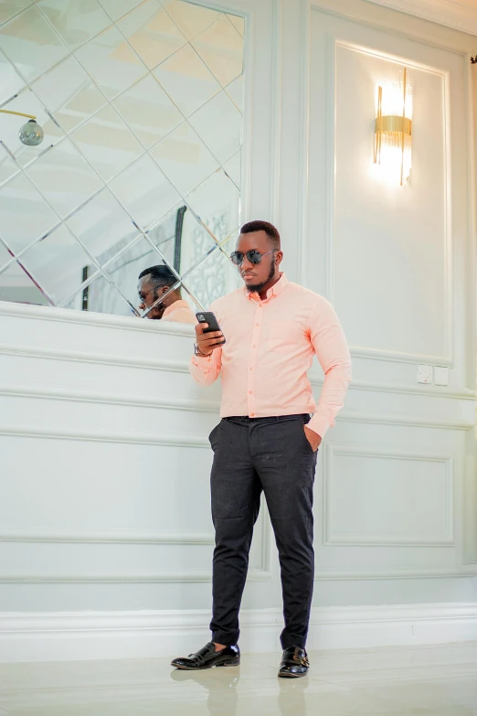 man in suit and sunglasses holding a cell phone next to wall