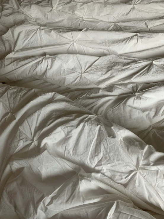 an wrinkled up mattress with a pillow behind it