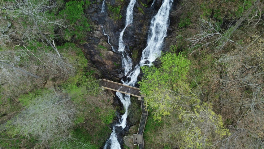 a bridge sits over a small waterfall with a walkway underneath