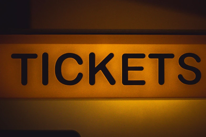 a ticket sign lit by a light that reads tickets