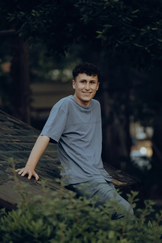 a boy smiling at the camera on top of a tree