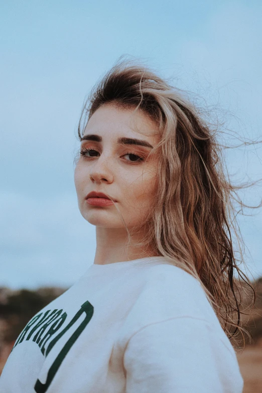 a woman is standing in the sand with her hair blowing in the wind