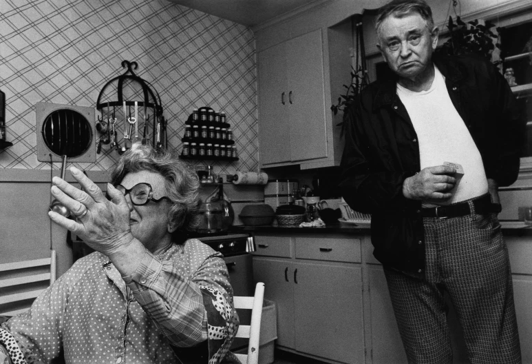 a couple of elderly people that are standing in a kitchen