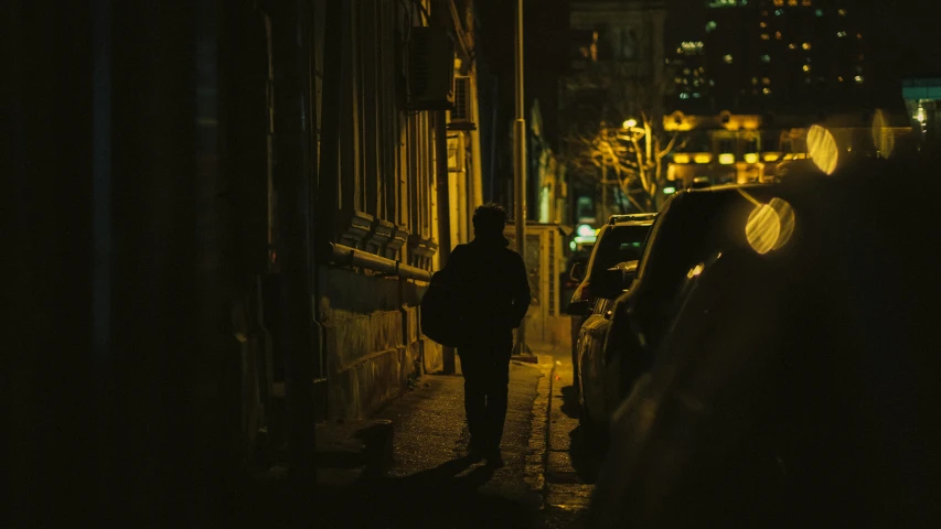 the man walks down a dark alley in his black outfit