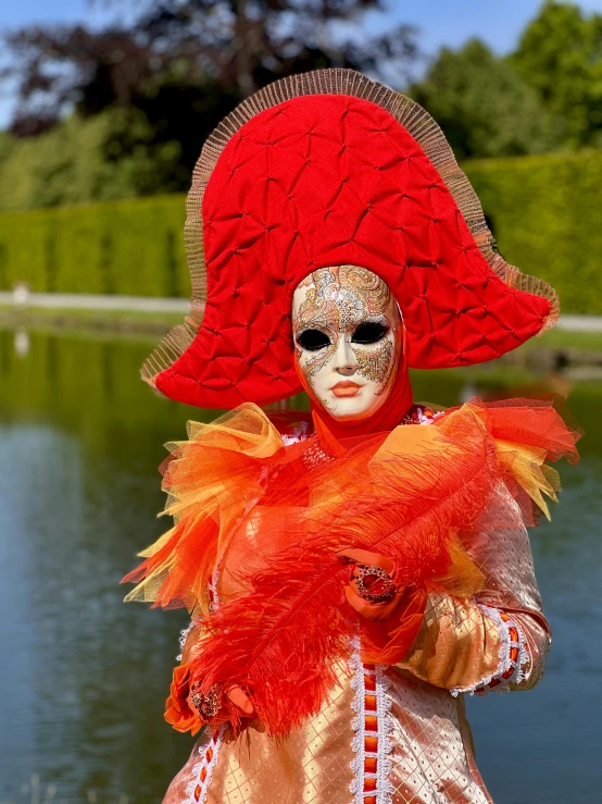 a lady in a mask and orange hair stands by the water