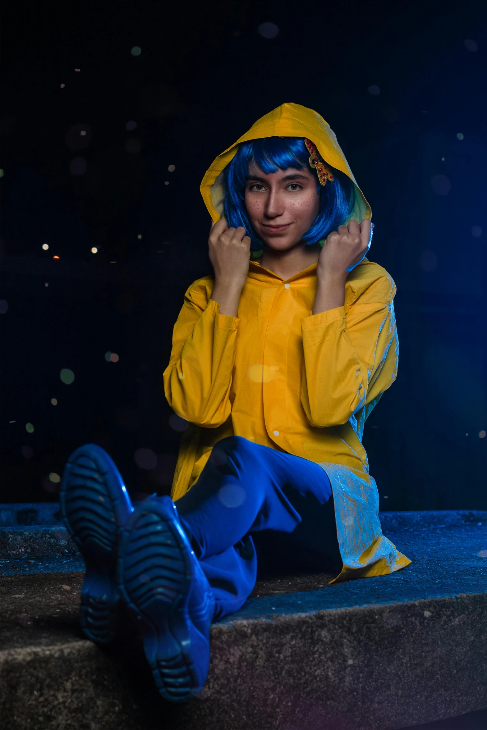 a woman with blue hair wearing a yellow jacket is sitting on a wall