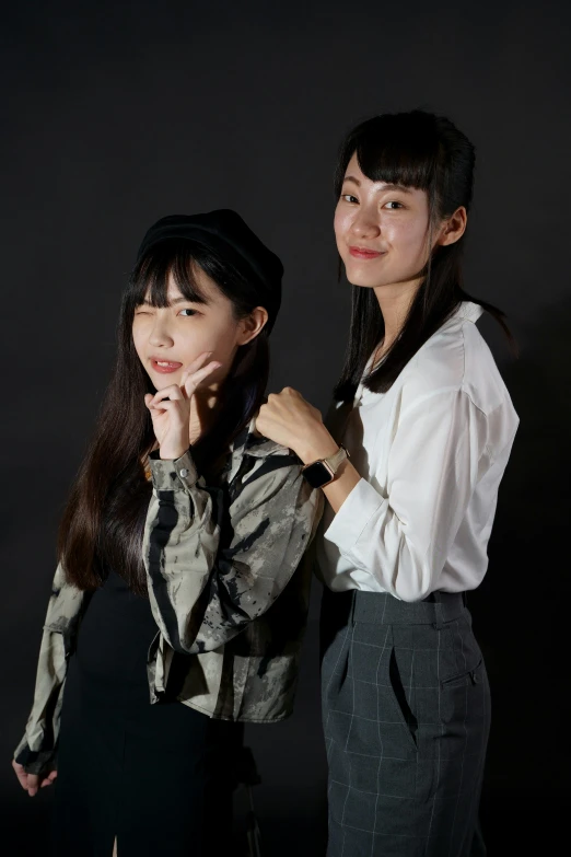 two girls pose for the camera, holding hands to their chest