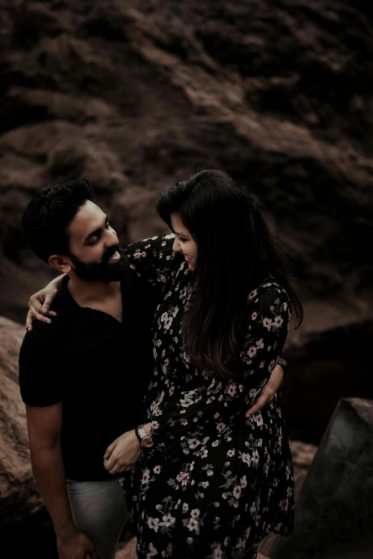 an affectionate couple emces in front of a rock outcropping