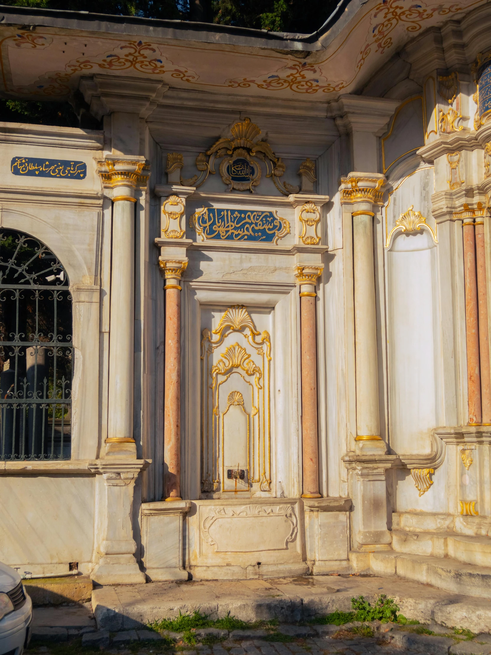 a building with columns and two doors is in front of a tree