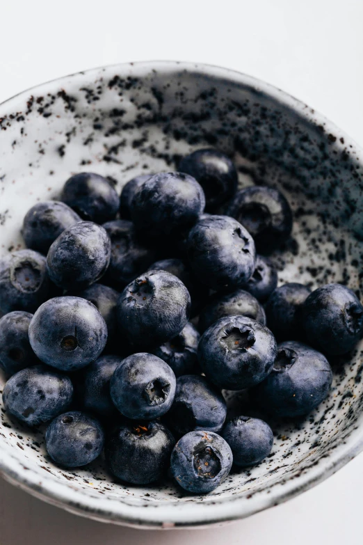 a bowl filled with blueberries on top of a table