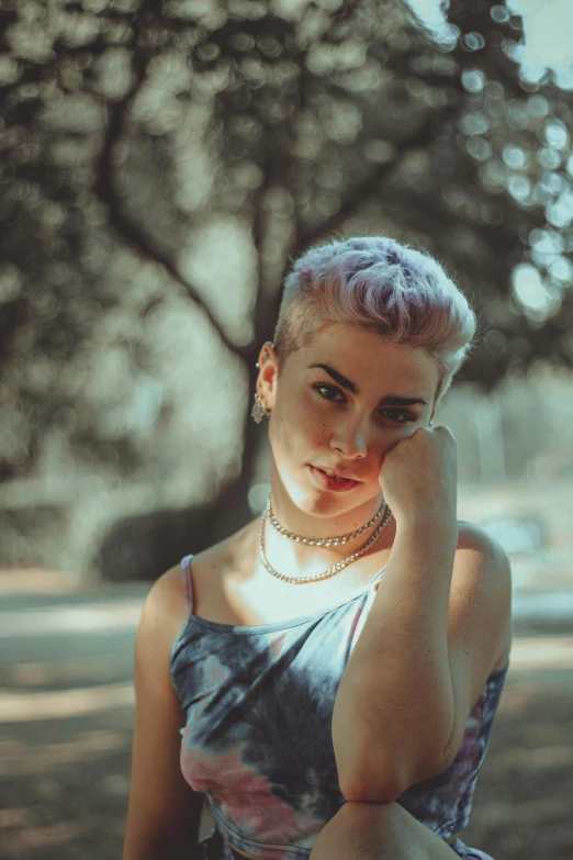 a girl with pink hair sits on a bench in a park