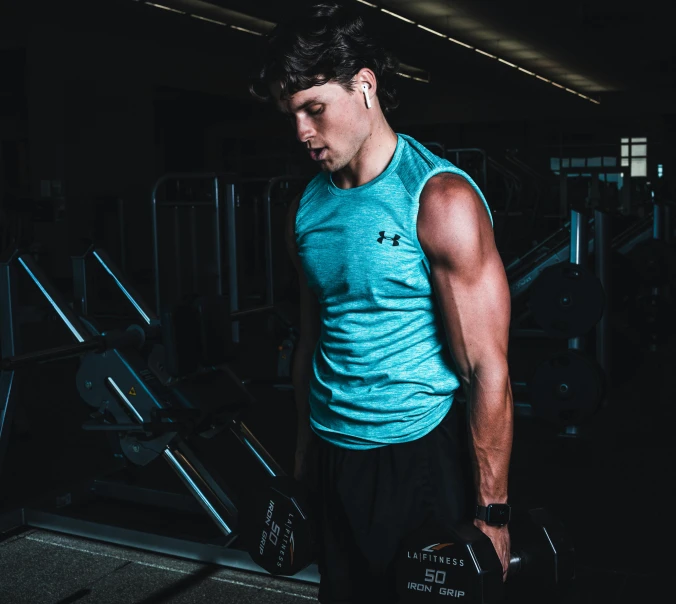 a man holding two weights in a gym