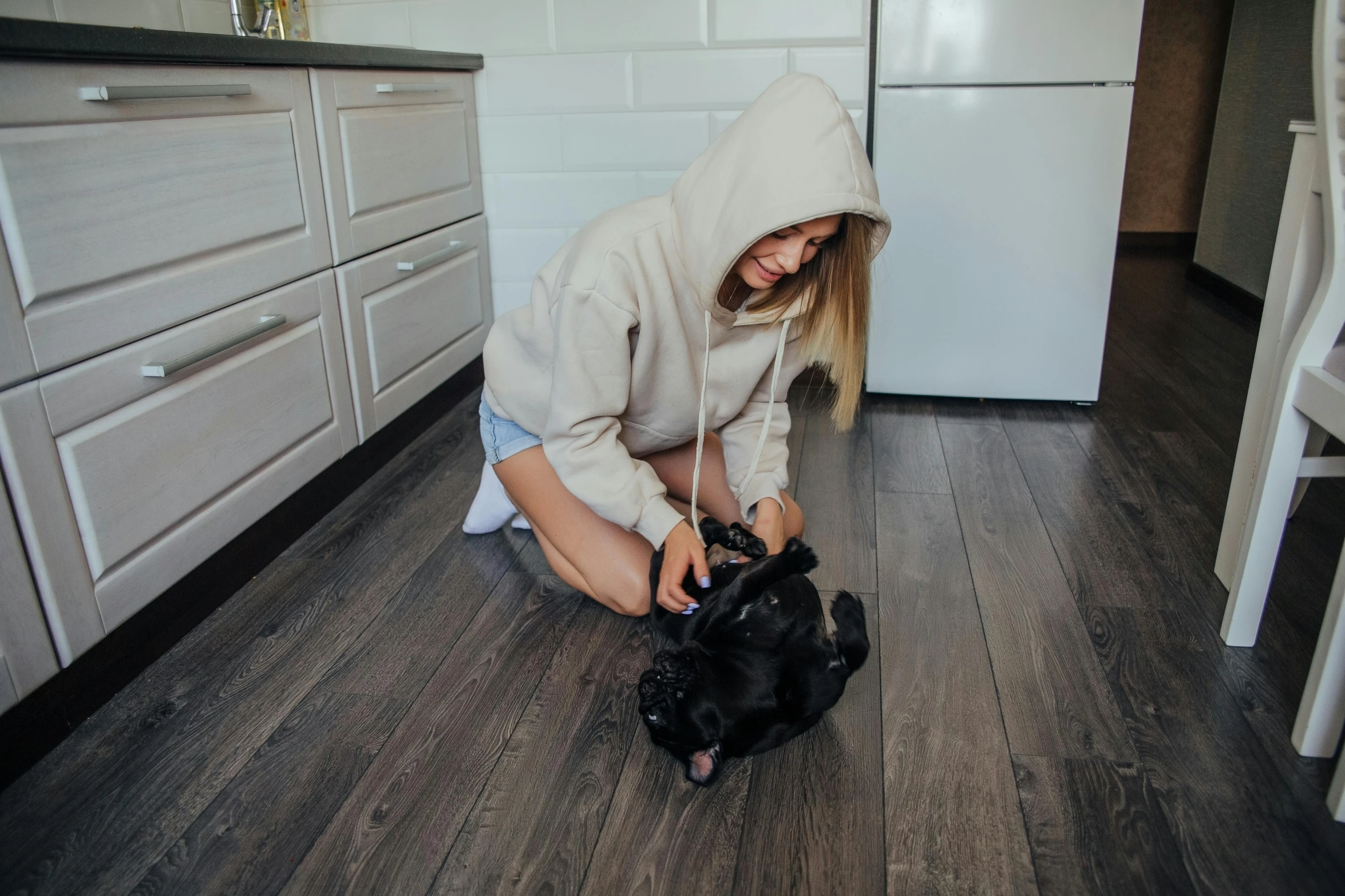 a woman kneeling down while holding a black cat