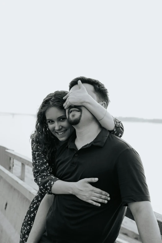 a couple standing by a rail in front of water