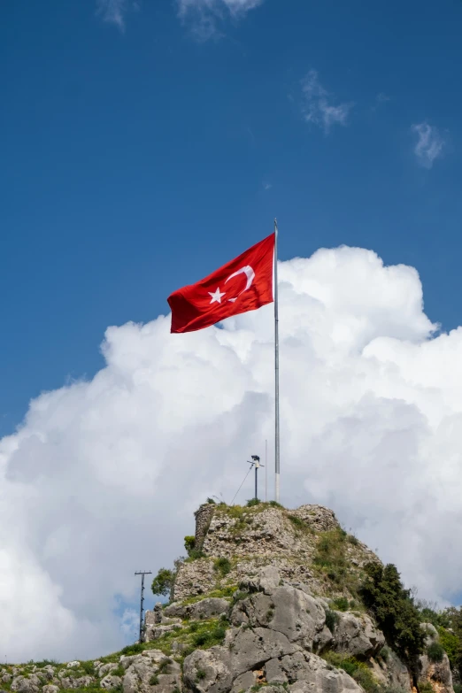 a flag is waving high in the air on top of a mountain
