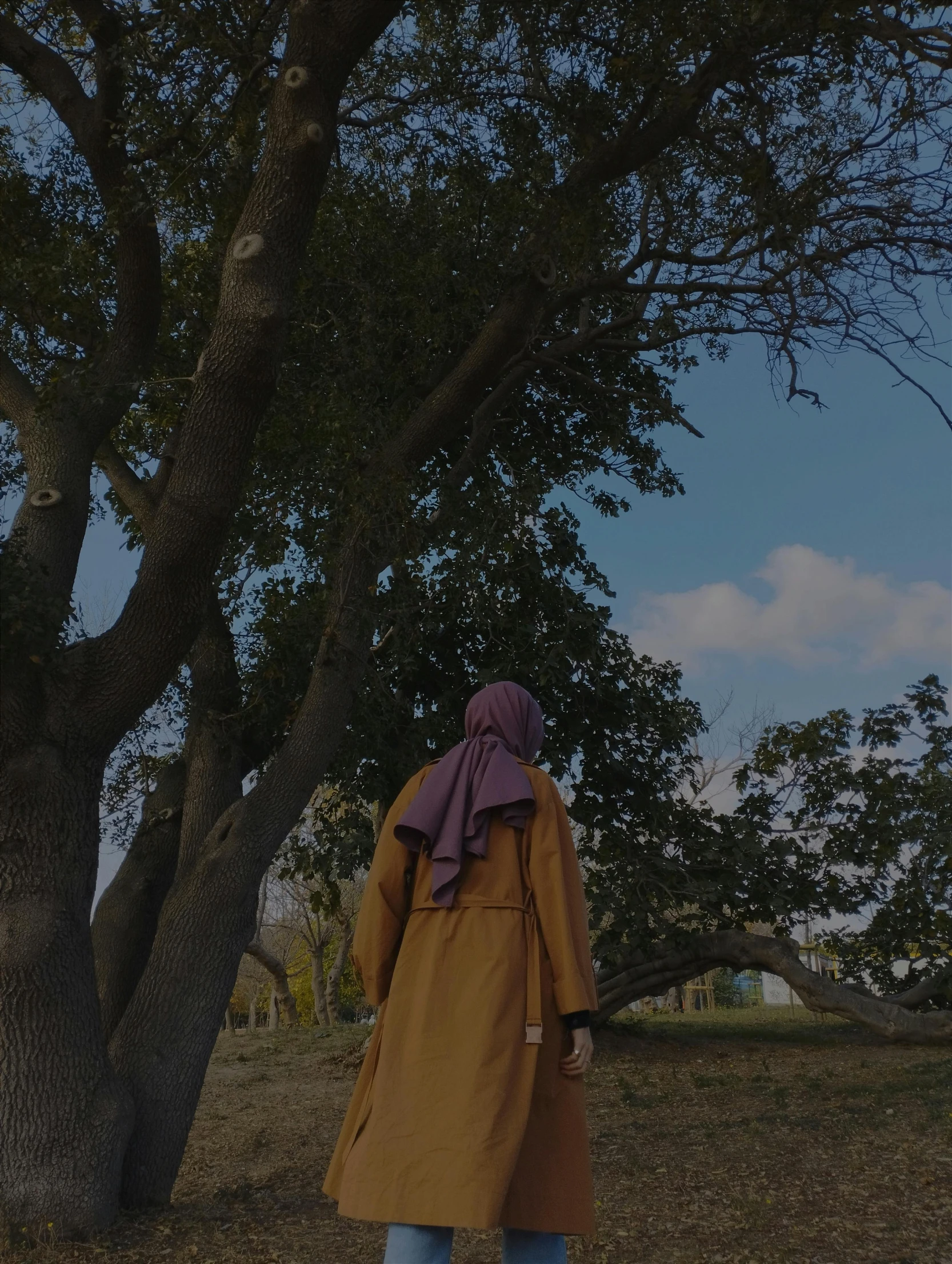 a woman in brown coat standing next to tree