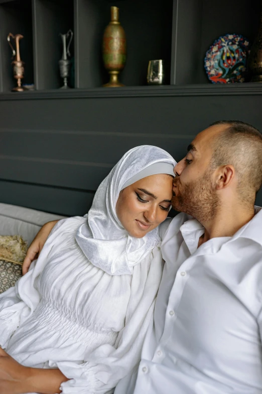 the man is kissing his pregnant wife in bed