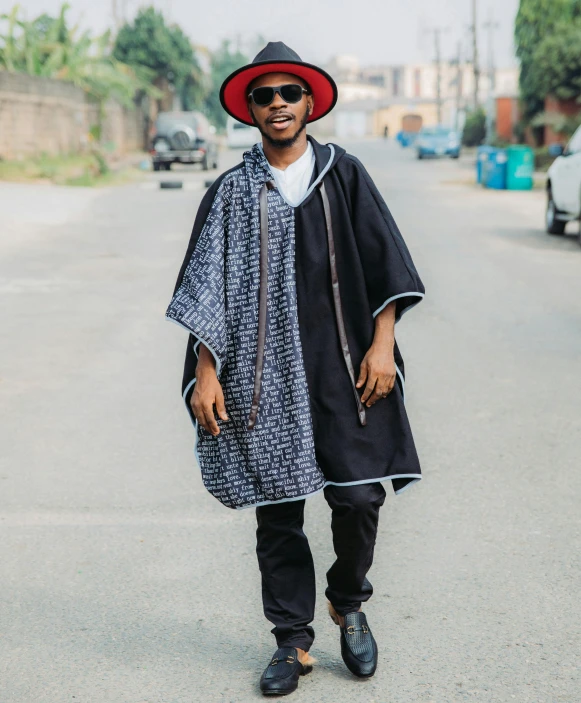 a man wearing a black cape and red hat