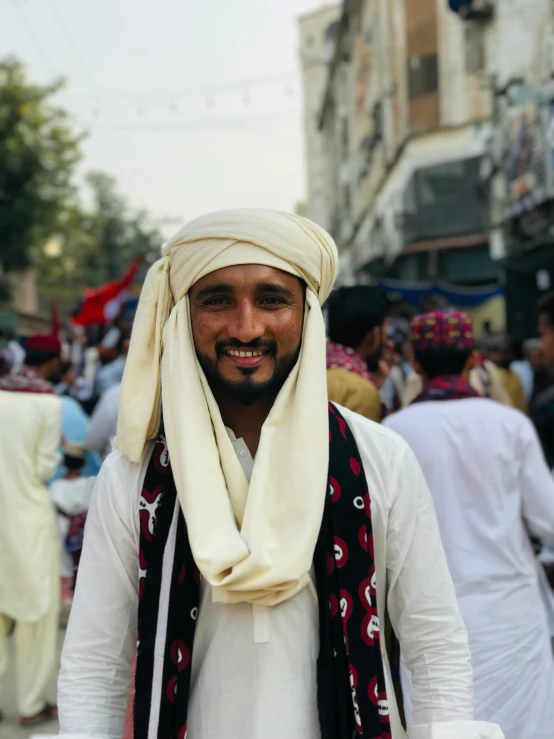 man with a long veil and a headdress is smiling at the camera