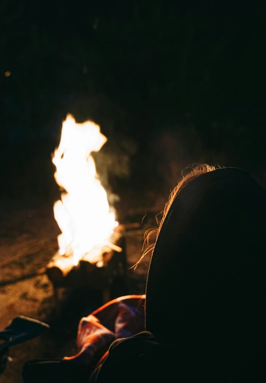 a woman sitting near a bonfire with soing in it