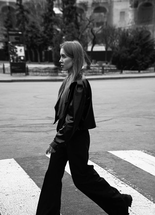 a woman walking across an cross walk in the middle of the road