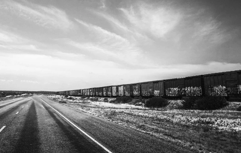 black and white pograph of a train passing by a country road